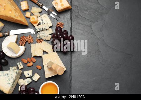 Käseplatte mit Spezialmesser und Gabel auf schwarzem Tisch, flach liegend. Platz für Text Stockfoto