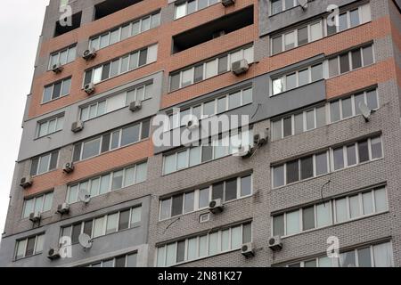 Mehrstöckige Häuser aus weißen, roten Ziegelsteinen, viele geschlossene Balkone und weiße Fenster. Das Haus steht in der Stadt Dnipro, Ukraine. Stockfoto