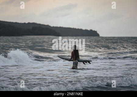 Ein Surfer bei Sonnenuntergang in Cenang Beach, Langkawi, Malaysia. Stockfoto