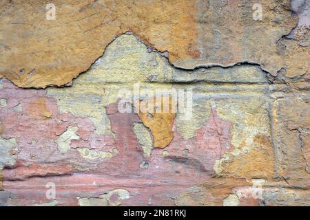 Die alten schäbigen Wände des alten Hauses, mit abblätternder Farbe gehauen, große und kleine Risse in der grauen Betonwand. Stockfoto