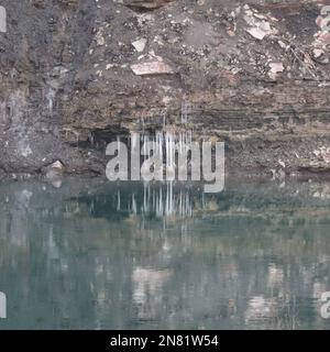 Eiszapfen werden in einem nicht vollständig gefrorenen Bereich reflektiert Stockfoto