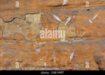 Die alten schäbigen Wände des alten Hauses, mit abblätternder Farbe gehauen, große und kleine Risse in der grauen Betonwand. Stockfoto