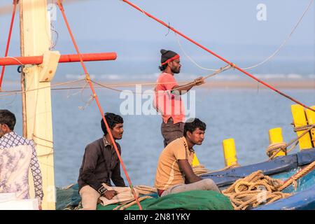 Diu, Indien - Dezember 2018: Fischer, die auf einem farbenfrohen Fischerboot vor der Küste der Insel Diu unterwegs sind. Stockfoto