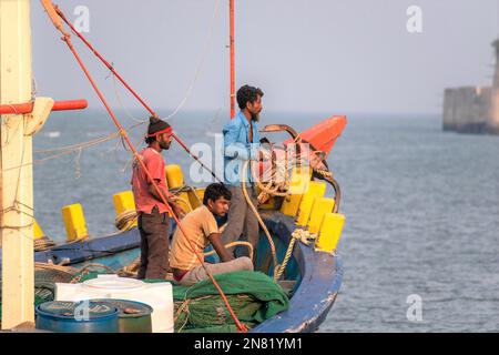 Diu, Indien - Dezember 2018: Fischer, die auf einem farbenfrohen Fischerboot vor der Küste der Insel Diu unterwegs sind. Stockfoto