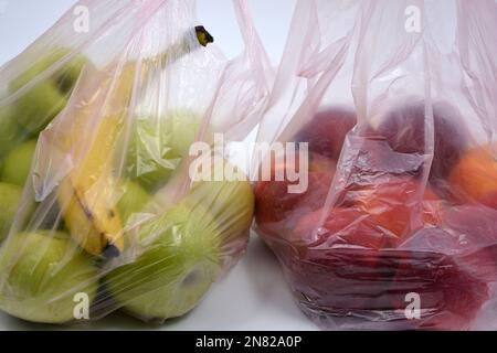 Zwei große Packungen Obst, gesunde Lebensmittel, viele rote, reife Äpfel und grüne Äpfel mit einer reifen Banane liegen in rosa Einwegbeuteln. Stockfoto