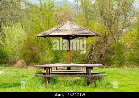 Alte hölzerne Gartenlaube, die neben der Straße in der Natur steht Stockfoto