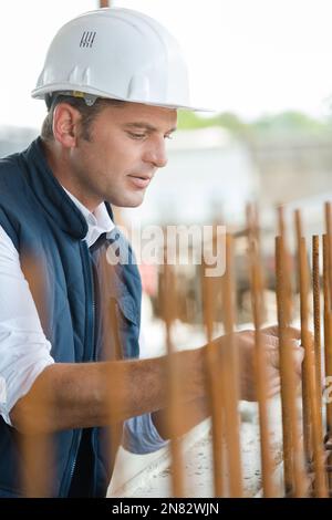 Mann, der in der Fabrik an einem Metallstab misst Stockfoto