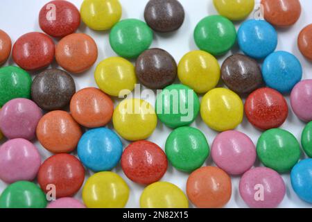 Bunte, bunte Schokoladenbonbons mit roten, blauen, gelben, grünen, rosafarbenen Orangefarbene Schokoladenbeschichtung auf weißem Hintergrund. Stockfoto