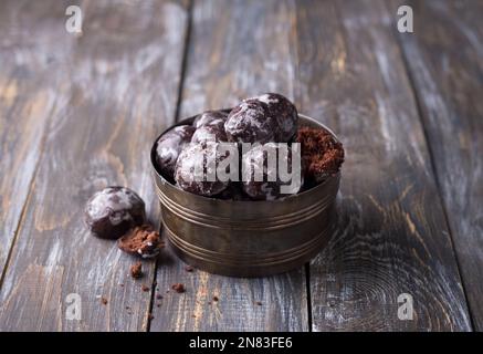 Weiche vegane, gedämpfte Schokoladen-Lebkekse mit Puderzucker in einer alten Schüssel auf einem Holztisch Stockfoto