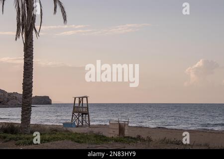 Rettungsschwimmturm an einem griechischen Strand bei Sonnenuntergang. Leerer Strand im Winter Stockfoto