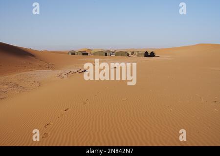 Berber-Camp in den Dünen von Erg Chigaga in der Sahara-Wüste im afrikanischen Südosten MAROKKOS, klarer blauer Himmel an 2023 warmen sonnigen Wintertag am Januar. Stockfoto