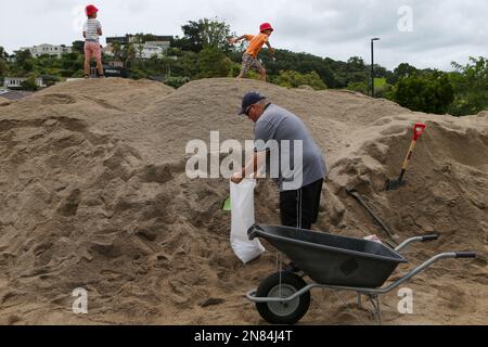 Aukland, Neuseeland. 11. Februar 2023. Ein Bewohner füllt einen Sandsack in einem temporären Sandlager in Auckland, Neuseeland, 11. Februar 2023. Neuseelands größte Stadt Auckland richtete temporäre Sandlagerstätten ein und stellte den Bewohnern Sandsäcke zur Verfügung, um sich auf neue Unwetterereignisse vorzubereiten. Die letzte Rekordregenrunde hat seit Januar 27 massive Überschwemmungen an Häusern und Grundstücken verursacht. Kredit: Zhao Gang/Xinhua/Alamy Live News Stockfoto