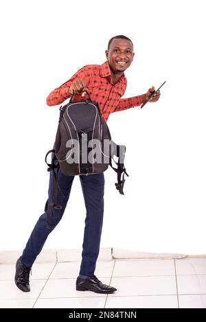 Junger Mann mit Rucksack und digitalem Tablet, während er vor der Kamera lächelt. Stockfoto