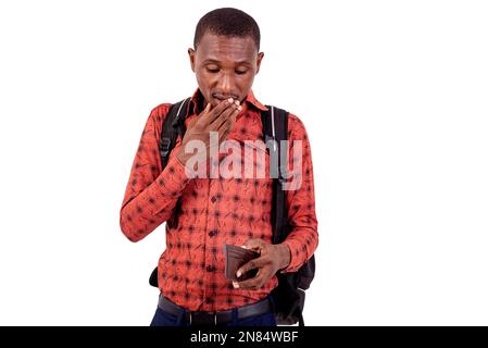 Porträt eines gut aussehenden, überraschten jungen Schülers, der Hand über Mund hält, während er in seine Brieftasche schaut. Stockfoto