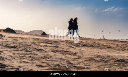 Zandvoort, Niederlande, 5. Februar 2023: Zwei Frauen gehen an einem windigen Tag die Sanddüne hinunter zum Strand Stockfoto