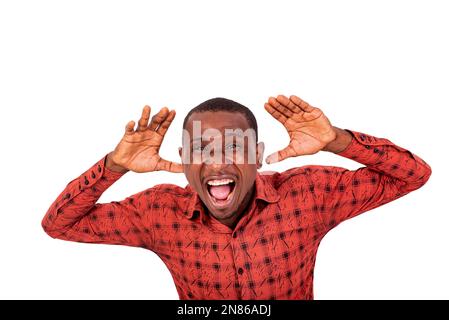 Ein junger Mann in einem karierten Hemd, der auf weißem Hintergrund steht und Gesichter macht. Stockfoto