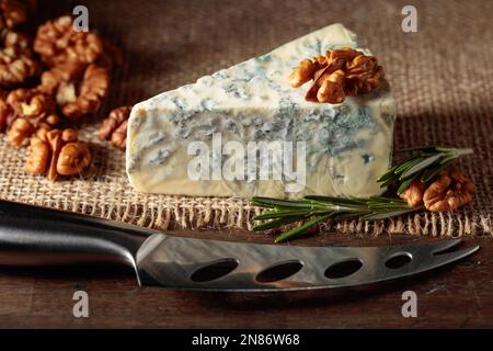 Blauer Käse mit Walnüssen und Rosmarin auf einem alten Holztisch. Stockfoto