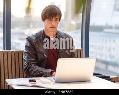 Geschäftsmann arbeitet mit Laptop- und Papierorganisator in einem Co-working Center zusammen. Arbeitsplatz für Freiberufler im Business Center. Stockfoto