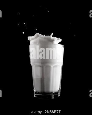 Milchtropfen in einem Glas auf schwarzem Hintergrund. Stockfoto