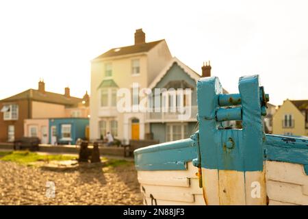 Flacher Fokus eines alten hölzernen Fischerboots an einer Kieselküste. Küstengebiete sind im Sommerlicht zu sehen. Stockfoto