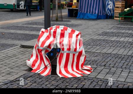 Straßenstromversorger auf dem kollektiven Agrarmarkt mit rot-weiß gestreifter Plane. Stockfoto