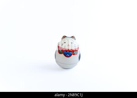 Ein Maneki-Neko oder auch bekannt als Glückskatze in Porzellan. Symbolisiert Glück und Reichtum, auf einem weißen, isolierten Hintergrund. Stockfoto