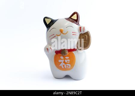 Ein Maneki-Neko oder auch bekannt als Glückskatze in Porzellan. Symbolisiert Glück und Reichtum, auf einem weißen, isolierten Hintergrund. Stockfoto