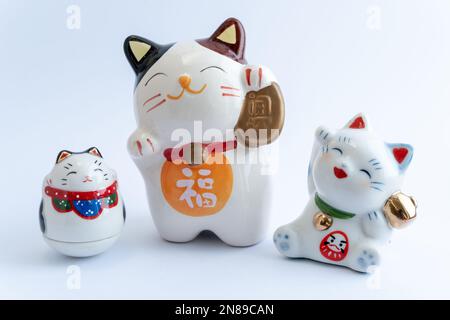 Ein Maneki-Neko oder auch bekannt als Glückskatze in Porzellan. Symbolisiert Glück und Reichtum, auf einem weißen, isolierten Hintergrund. Stockfoto