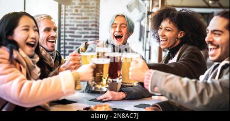 Fröhliche Freunde trinken und toasten Bier im Brauereirestaurant - das Speise- und Getränkekonzept mit jungen, vielfältigen Menschen, die Spaß miteinander haben Stockfoto