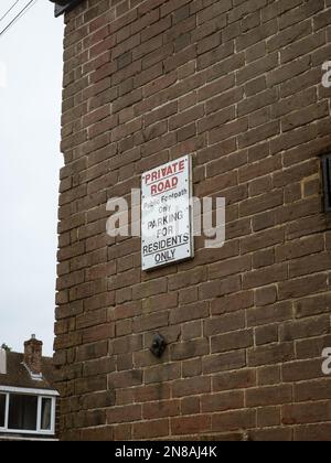 Ein vertikales Bild eines privaten Straßenschilds an der Seite eines Ziegelmauergebäudes Stockfoto