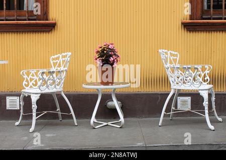 Weiß lackiertes hölzerne Patio-Möbel im Freien in einem befestigten Winkel eines Gartens Stockfoto