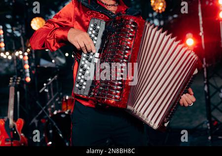 Der Musiker spielt Akkordeon. Eine Hand spielt das Akkordeon Nahaufnahme. Akkordeonist. Akkordeon. Stockfoto