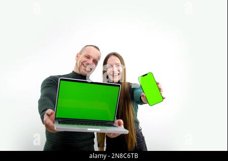 Ein Mann und ein Mädchen teilen sich einen Kauf mit, in dem sie Angebote für einen Verkaufsleiter in einem Geschäft präsentieren, die neue Geräte vorführen, einen Computer und ein Mobiltelefon, Vater und Tochter Einer jungen Familie Stockfoto