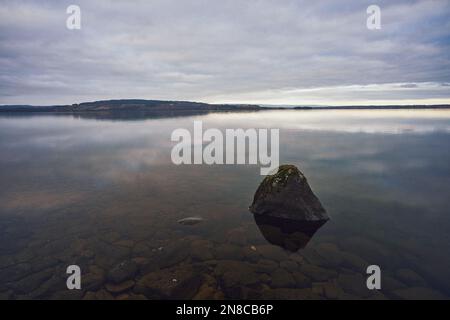 Eine wunderschöne Aufnahme des klaren Mjosa-Sees unter dem hellen Abendhimmel in Toten, Norwegen Stockfoto