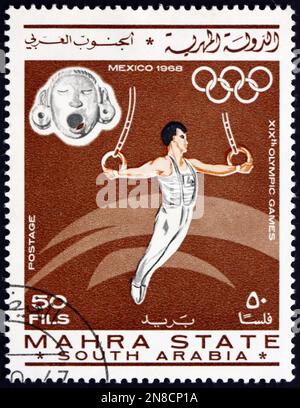 BUNDESSTAAT MAHRA - CA. 1967: Ein in Mahra Sultanate gedruckter Stempel zeigt Gymnastik, Olympische Sommerspiele 1968, Mexiko-Stadt, ca. 1967 Stockfoto