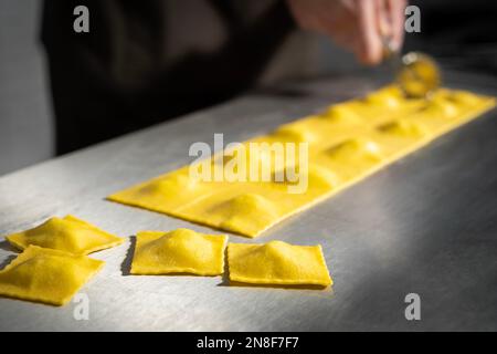 Zubereitung von frisch zubereiteten Ravioli mit Ricotta-Käse in einer Nudelfabrik. Ich mache vier Käseravioli. Stockfoto