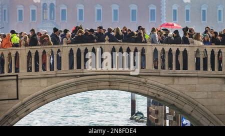 Venedig, Italien. 11. Februar 2023. Eine dicht gepackte Brücke in Riva degli Schiavoni am Ufer. In den zentralen Gegenden von Venedig sind für den Karneval 2023, dem ersten Jahr, in dem nach Covid wieder volle Feierlichkeiten stattfinden, vollgepackte Straßen, Boulevards und Brücken zu sehen. Am Nachmittag schätzte die örtliche Polizei, dass ca. achtzigtausend Feiern, Besucher und Einheimische allein in der Gegend um den Markusplatz waren. Venedig sonnte sich heute in der wunderschönen Sonne, die vielleicht noch mehr Menschen dazu gebracht hat, mitzumachen. Kredit: Imageplotter/Alamy Live News Stockfoto