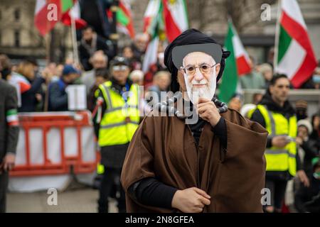 London, Vereinigtes Königreich - 11. Februar 2023: Chamenei – der oberste Führer des Iran – wird in einer Aufführung von Demonstranten dargestellt. Heute ist der 44. Jahrestag der Islamischen Revolution im Iran. Nach mehr als fünf Monaten anhaltender Proteste zur Unterstützung der Frau, des Lebens und der Freiheitsbewegung versammelten sich Tausende von Demonstranten auf Trafalgar Square. Das Regime im Iran anzuprangern. Die Demonstranten hielten die Shir-o-Khorshid-Flagge (Löwe und Sonne) des Iran – die Flagge oder ihr Emblem waren jahrhundertelang Teil der iranischen nationalen Identität – die sich nach der Islamischen Revolution im Jahr 1979 änderte. Kredit: Sinai Noor/Alamy Live News Stockfoto