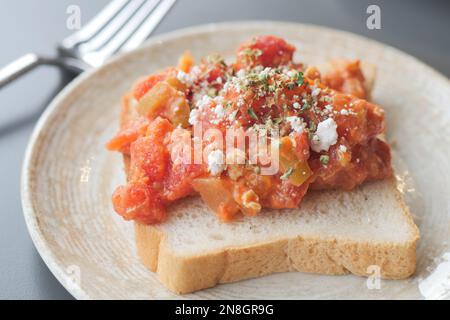 Rührei mit Tomaten auf Brötchen auf einem Teller Stockfoto