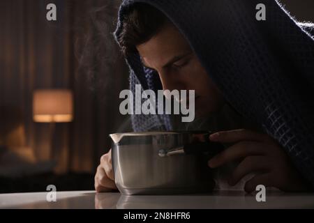 Ein Mann mit Karomuster inhaliert über dem Saucetopf im Haus Stockfoto