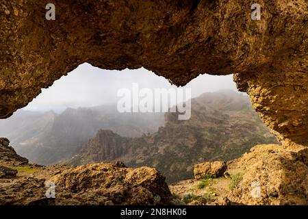 Blick auf das Tal durch den Felsenbogen Ventana del Nublo. Tageslicht. Bewölktes Wetter, niedrige Wolken. Keine Menschen. Stockfoto