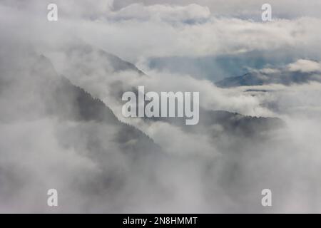 Die Bergketten der Alpen, die im Januar 2023 durch Wolken und Nebel gesehen wurden Stockfoto