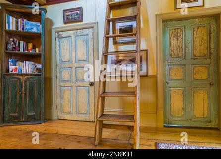 Flur mit breiten Pinienholzdielen, Miller's Treppen, Bücherregal und verstörten Schlafzimmertüren im oberen Stockwerk in einem alten Haus um 1805. Stockfoto