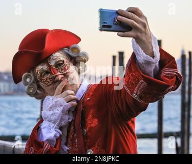 Venedig, Italien. 11. Februar 2023. Ein Feigling nimmt ein Selfie. Kostümierte Karnevalsteilnehmer und Feier mischen sich mit Touristen, Besuchern und Einheimischen, während das Karnevalswochenende in den Straßen und Plätzen von Venedig voll in Fahrt kommt. Kredit: Imageplotter/Alamy Live News Stockfoto