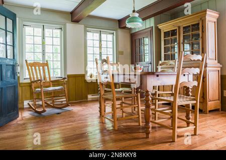 Esszimmer mit Kiefernholztisch und gewebten Sitzstühlen, Schaukelstuhl, Fichtenholzdielen im alten Haus von 1809. Stockfoto