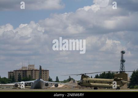 Ein Boeing CH 47 Chinook Helikopter mit der US-Armee vor einem USAF C17 Globemaster-Frachtflugzeug am Yokota Airbase, Fussa, Tokio, Japan. Stockfoto