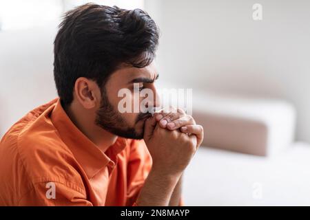 Frustrierter araber, der zu Hause auf dem Sofa saß und die Tür aufmachte Stockfoto