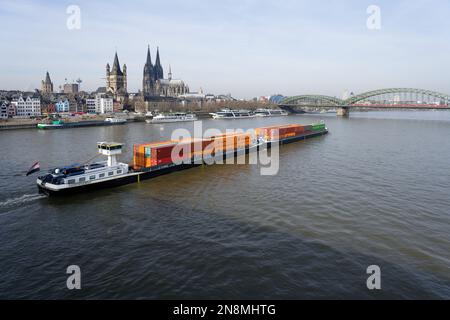 Ein langes Containerschiff mit einem Schubschiff fährt auf dem rhein durch köln Stockfoto