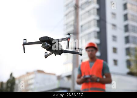 Bauarbeiter, die Drohne mit Fernsteuerung auf der Baustelle bedienen. Luftaufnahmen Stockfoto
