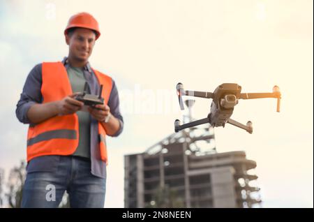 Bauarbeiter, die Drohne mit Fernsteuerung auf der Baustelle bedienen. Luftaufnahmen Stockfoto